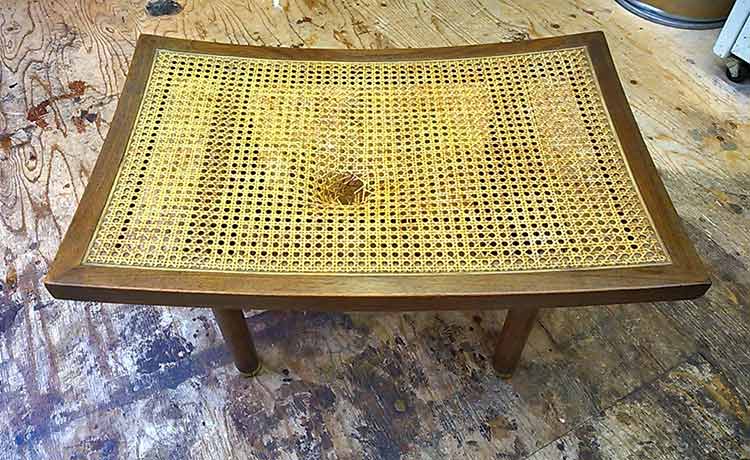Walnut bench with a hole in the cane seat